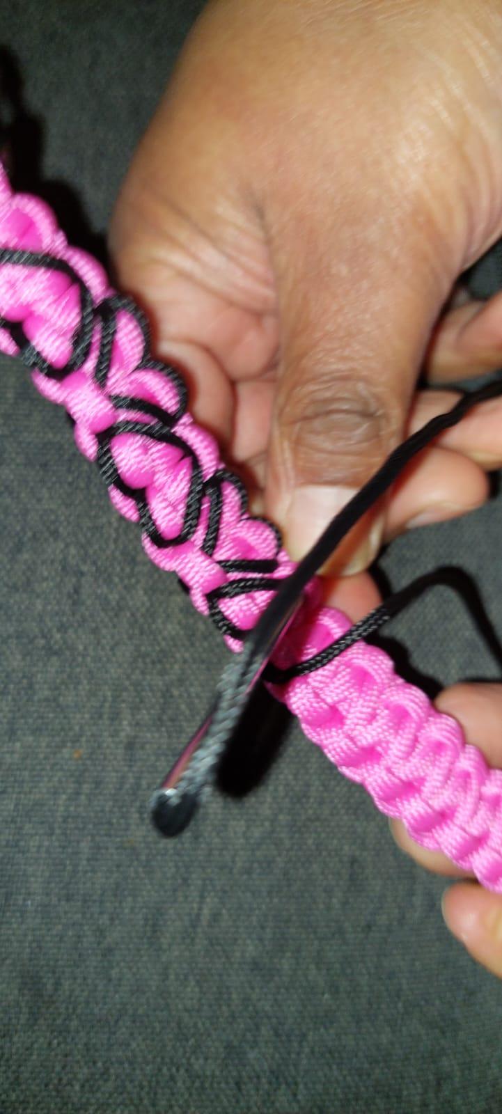 Gwendolyn haar handen zijn in beeld terwijl ze een paracord armbandje aan het maken is